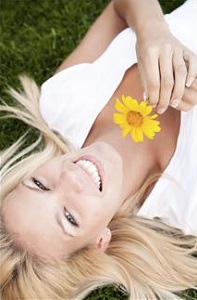 Woman laying in grass with flower