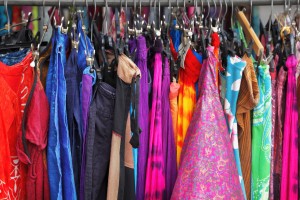 A closet rack stuffed with brightly colored clothes