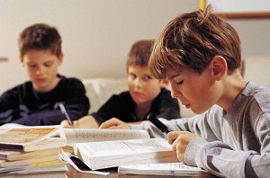 Boy does homework while two others watch