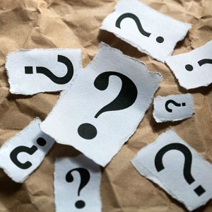 Papers with different sized question marks lay scattered on a table.