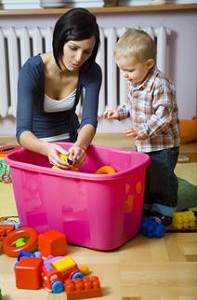 Mother and toddler putting away toys
