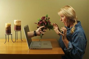 Hand with flowers coming out of laptop screen