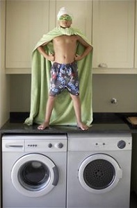 Boy with sheet cape standing on washing machine