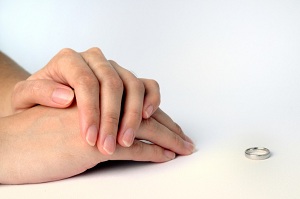 Folded hands and wedding ring resting on table