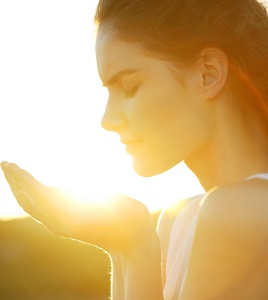 Side view of woman with hands cupped in sunlight