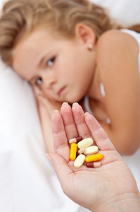 Wary child and mother's hand full of pills