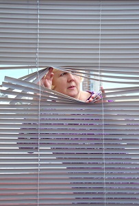 Woman peeking through blinds