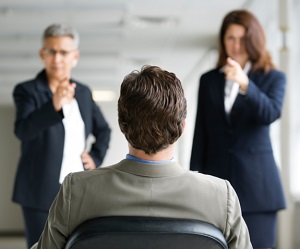 Two people pointing at a man in a chair