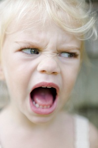Headshot of angry young child yelling