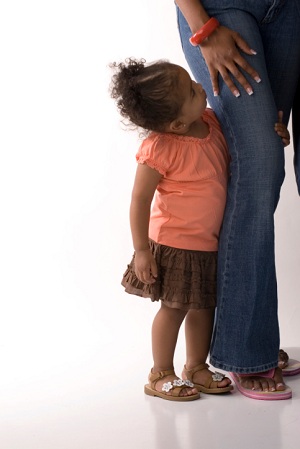 Toddler holding on to her mother's leg