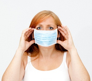 Woman holding medical mask over nose and mouth