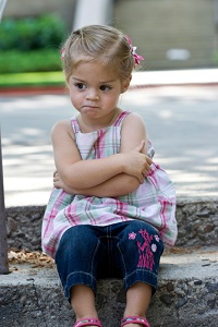 Angry toddler sitting with arms crossed