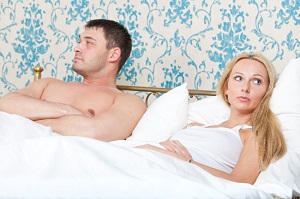 Couple in bed looking away from each other