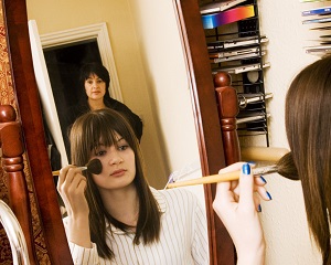 Reflection of girl in mirror with mother watching