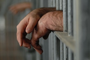 Hands resting on prison bars