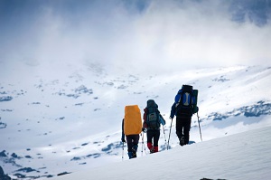 Three people hiking down mountain with backpacks