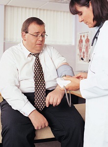 Overweight man having his blood pressure taken by a nurse