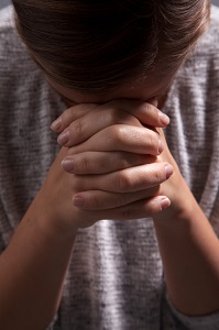 Person bowing head on clasped hands
