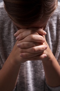 Person bowing head on clasped hands