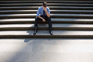 Man in business clothes sits on steps with his head on his hand