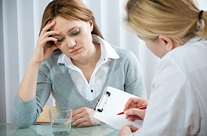 Stressed woman talking to doctor with notes