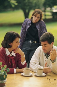 Parents talk while teen watches in background