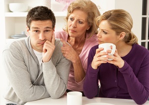 Woman looking at husband while her mother scolds him