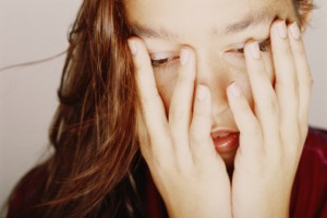 Woman covering face with hands, looking down