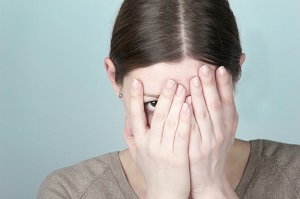 Woman covering face and peeking through fingers
