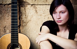 Woman sitting next to guitar
