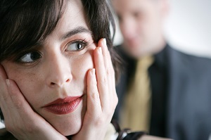 Woman holding face with man in background