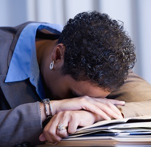 Stressed woman placing her head on her desk