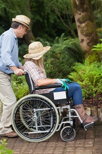 man-pushing-wife-in-wheelchair-through-garden