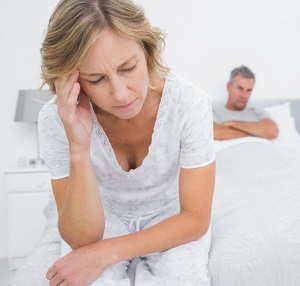 Upset couple sitting on opposite ends of bed