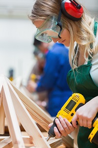 Drilling woman in a woodwork class