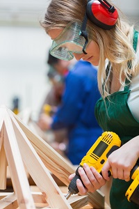 Drilling woman in a woodwork class