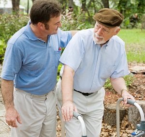 male caregiver walks with elderly man