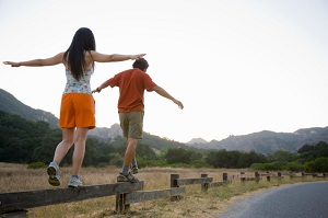 man-and-woman-balancing-while-walking-on-fence