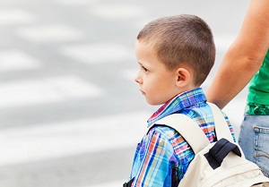 young boy crossing street to school