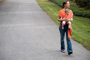 mother walking with baby in sling