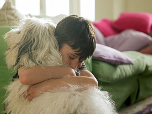 young boy hugging his dog