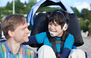 boy in wheelchair laughing with father