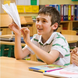 young boy in class with paper airplane