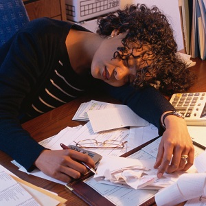 Woman sleeping at desk, papers around her