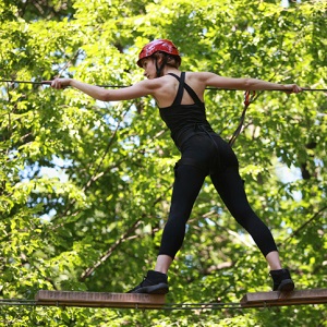 Young woman climbing in adventure rope park