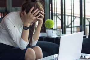 Young professional sits next to laptop, worried