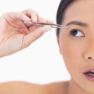 apprehensive woman using tweezers