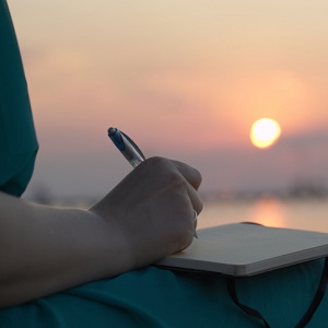 Woman writing in her diary at sunset