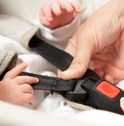 A hand buckles baby into carseat