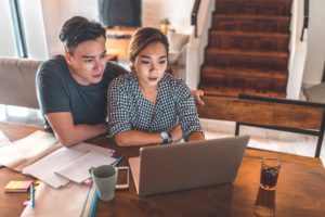 Couple sits at their table looking at the computer together, searching for a couples therapist